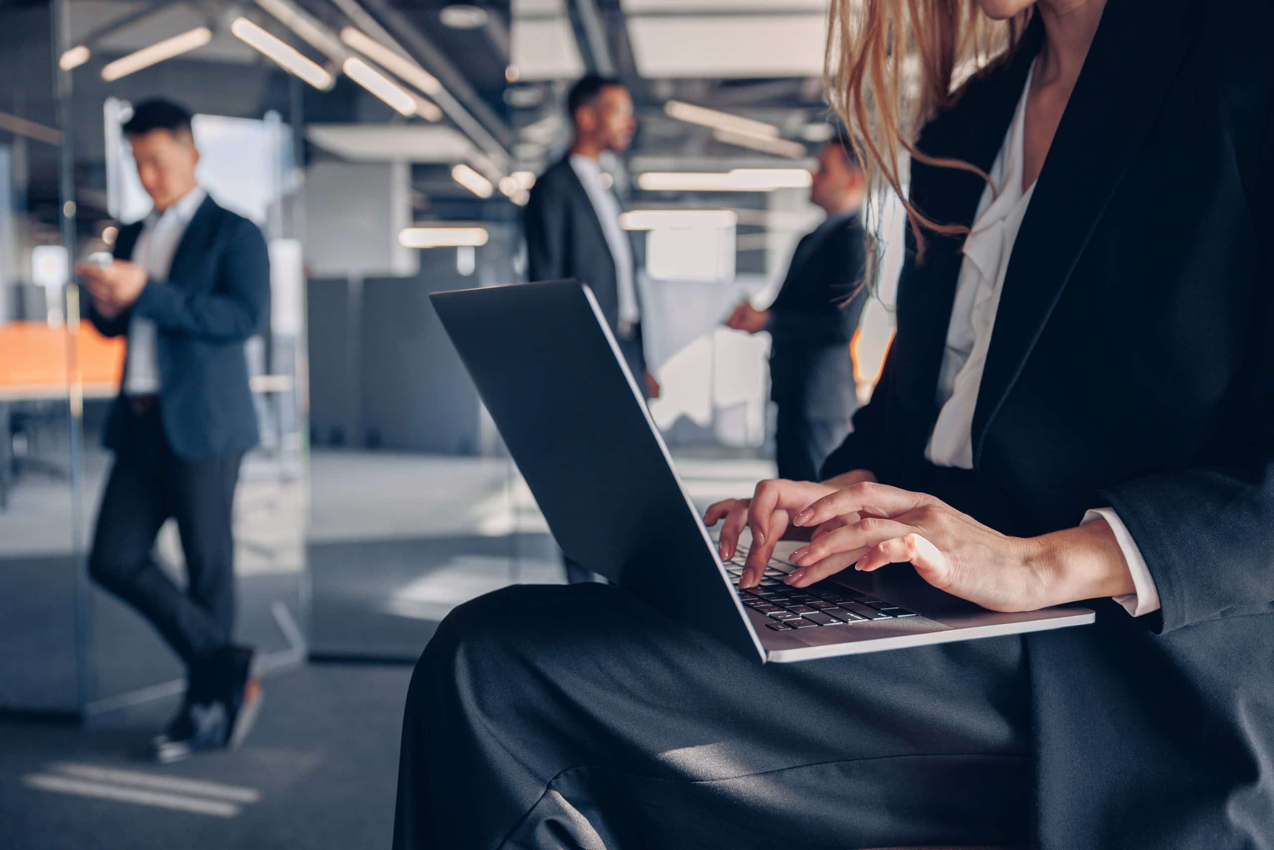 Close up of unrecognisable businesswoman working on laptop in office on colleagues background